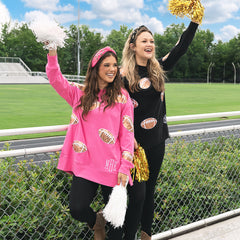 girls wearing hot pink and black monogrammed sequin sports sweatshirts at stadium
