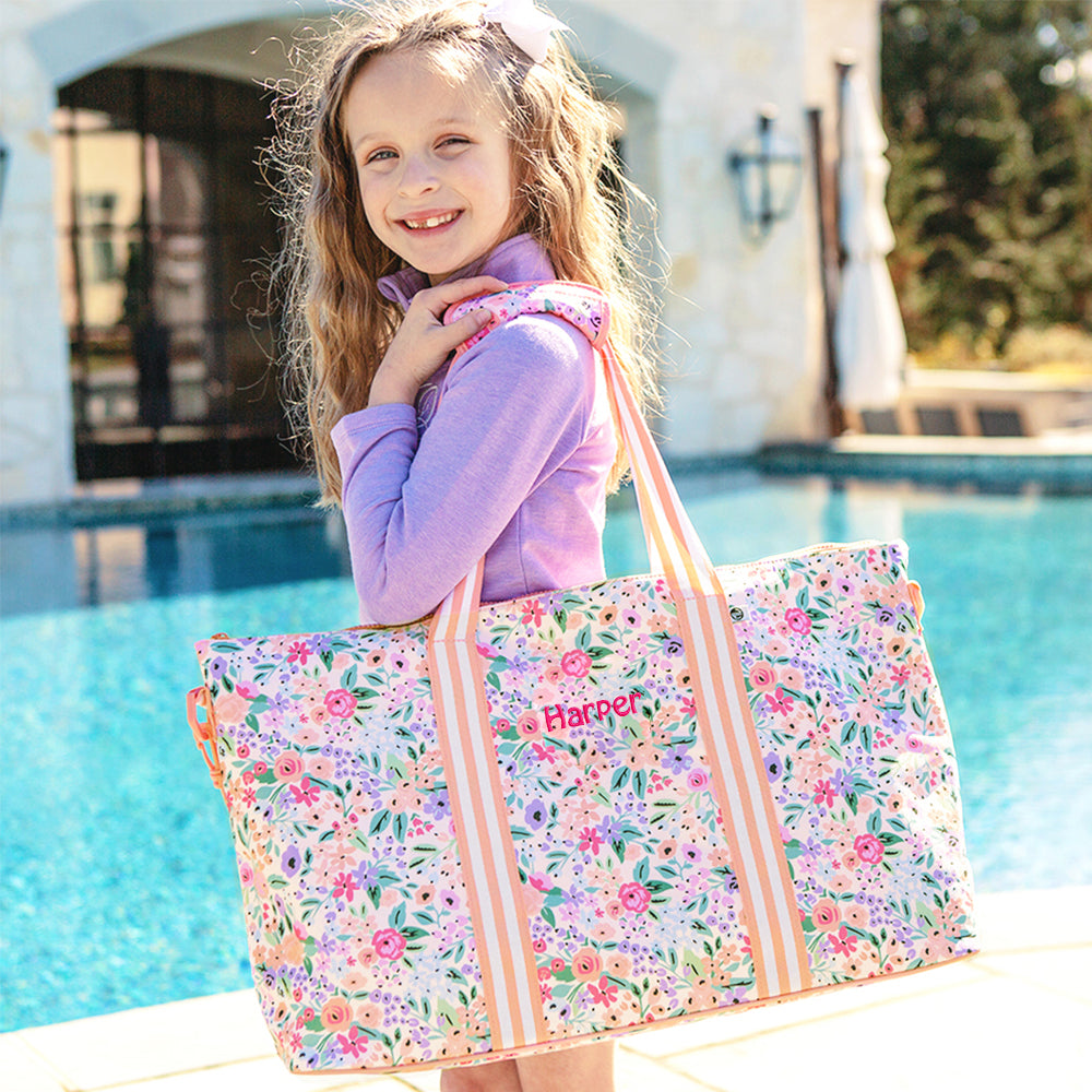 Young girl holding a floral tote bag by a pool