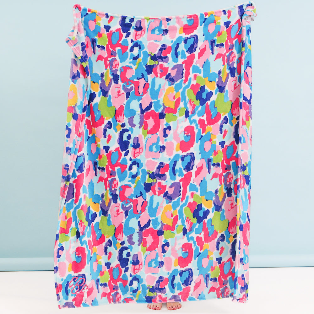 girl holding up monogrammed watercolor cheetah blanket