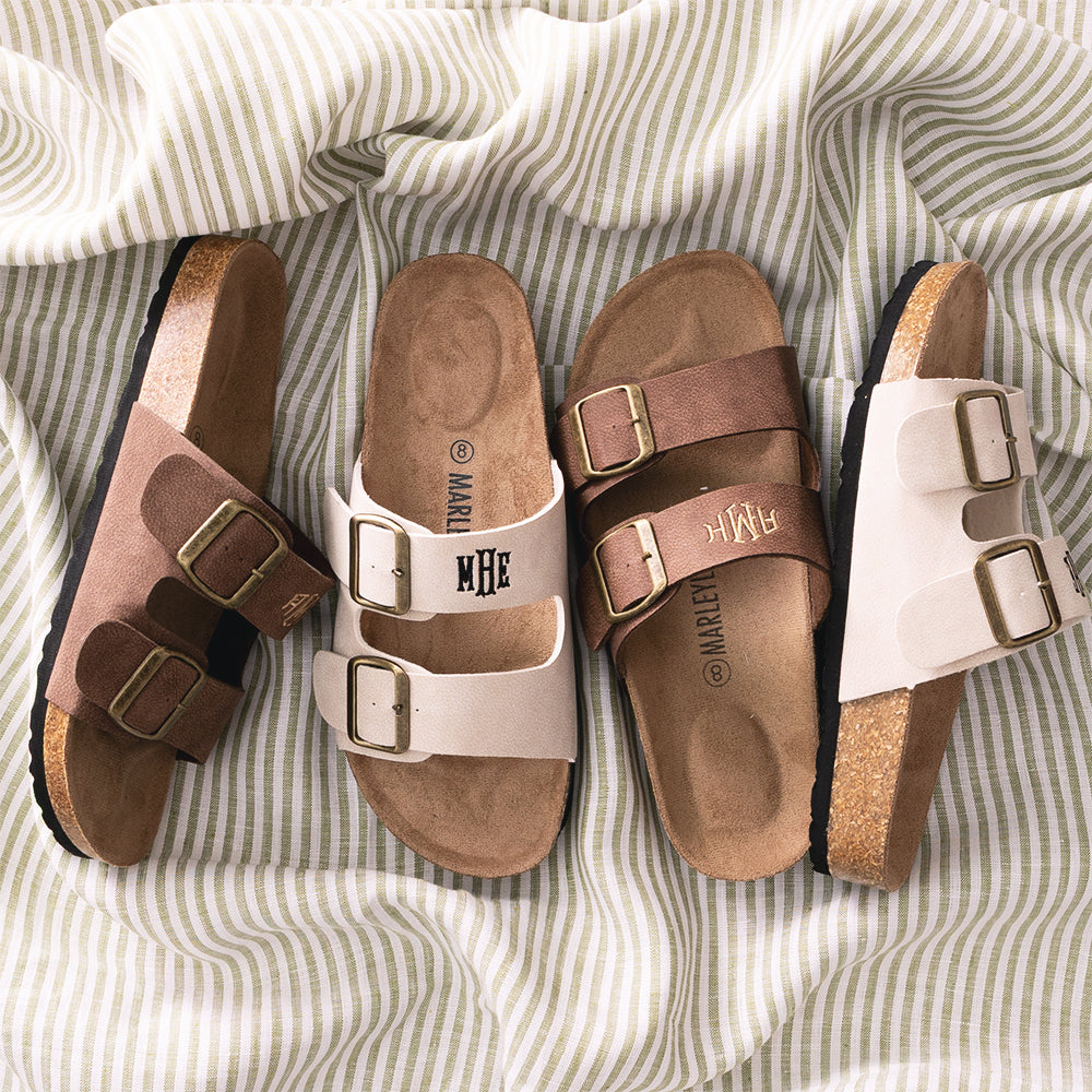 Four pairs of double strap sandals on a striped fabric background