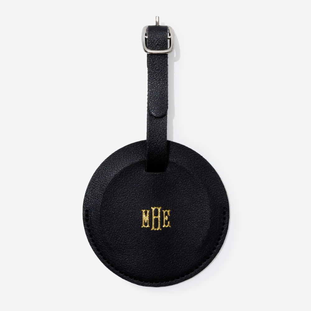 Black leather luggage tag with gold monogram on a white background