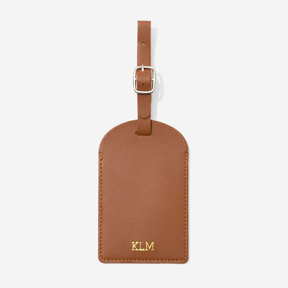 Brown leather luggage tag with gold monogram on a white background