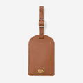 Brown leather luggage tag with gold monogram on a white background