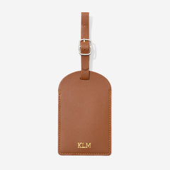 Brown leather luggage tag with gold monogram on a white background