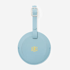 Mint leather luggage tag with gold monogram on a white background