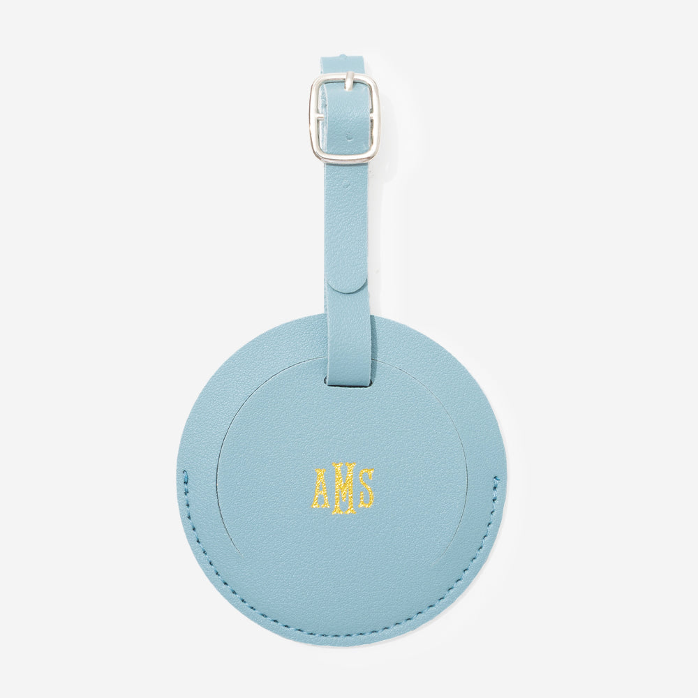 Mint leather luggage tag with gold monogram on a white background