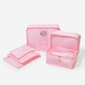 Set of pink mesh packing cubes with a monogram on a white background