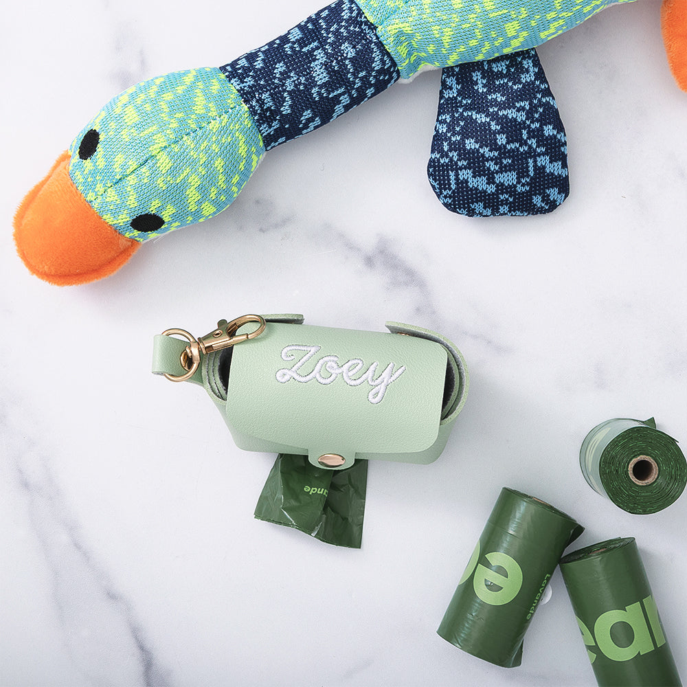 close up of mint monogrammed pet waste holder with dog toy