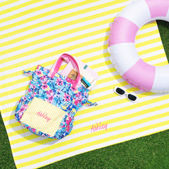 yellow striped beach towel with floral toiletry bag and pool float.
