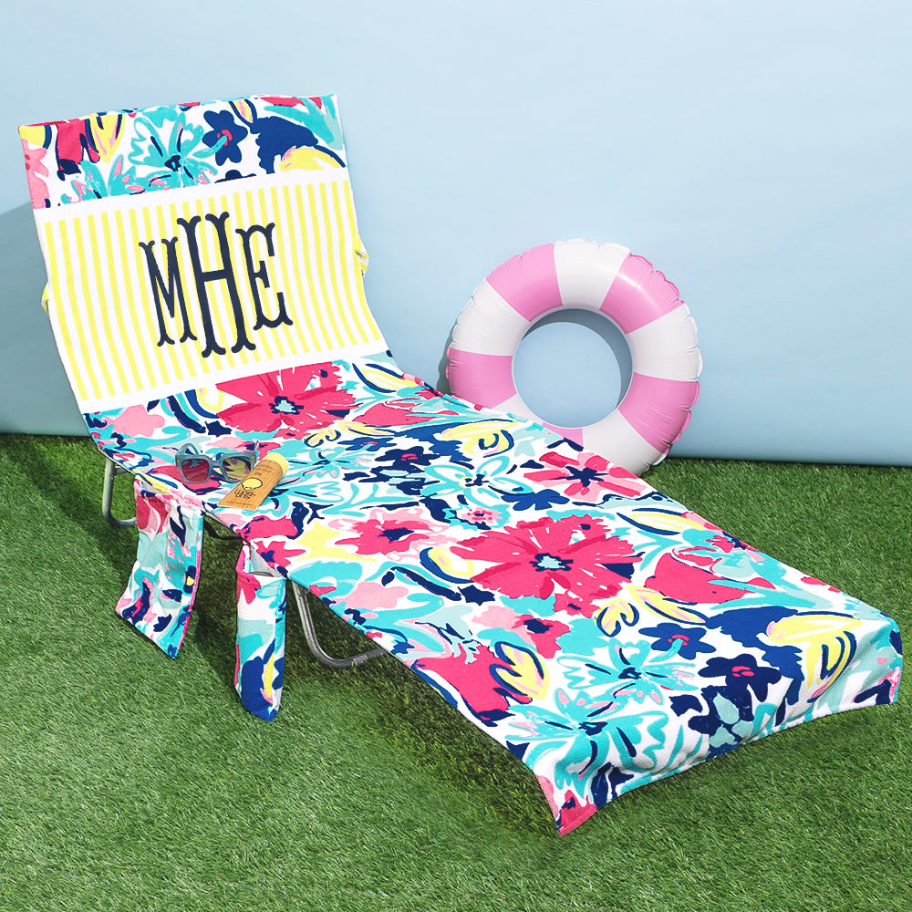 monogrammed pool chair cover with floral design and yellow and white stripes block at top.