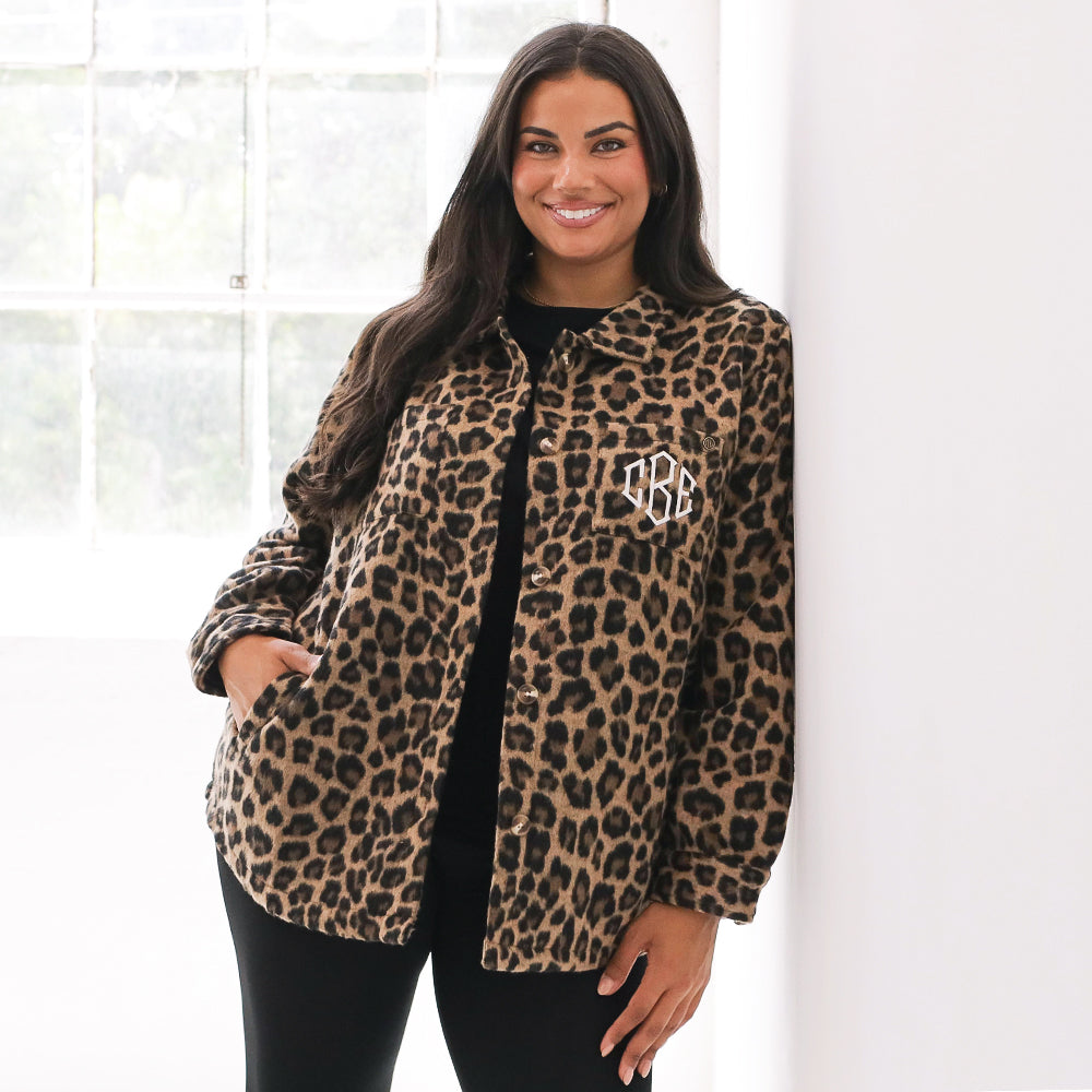 Woman wearing a leopard print jacket with a monogram on a white background