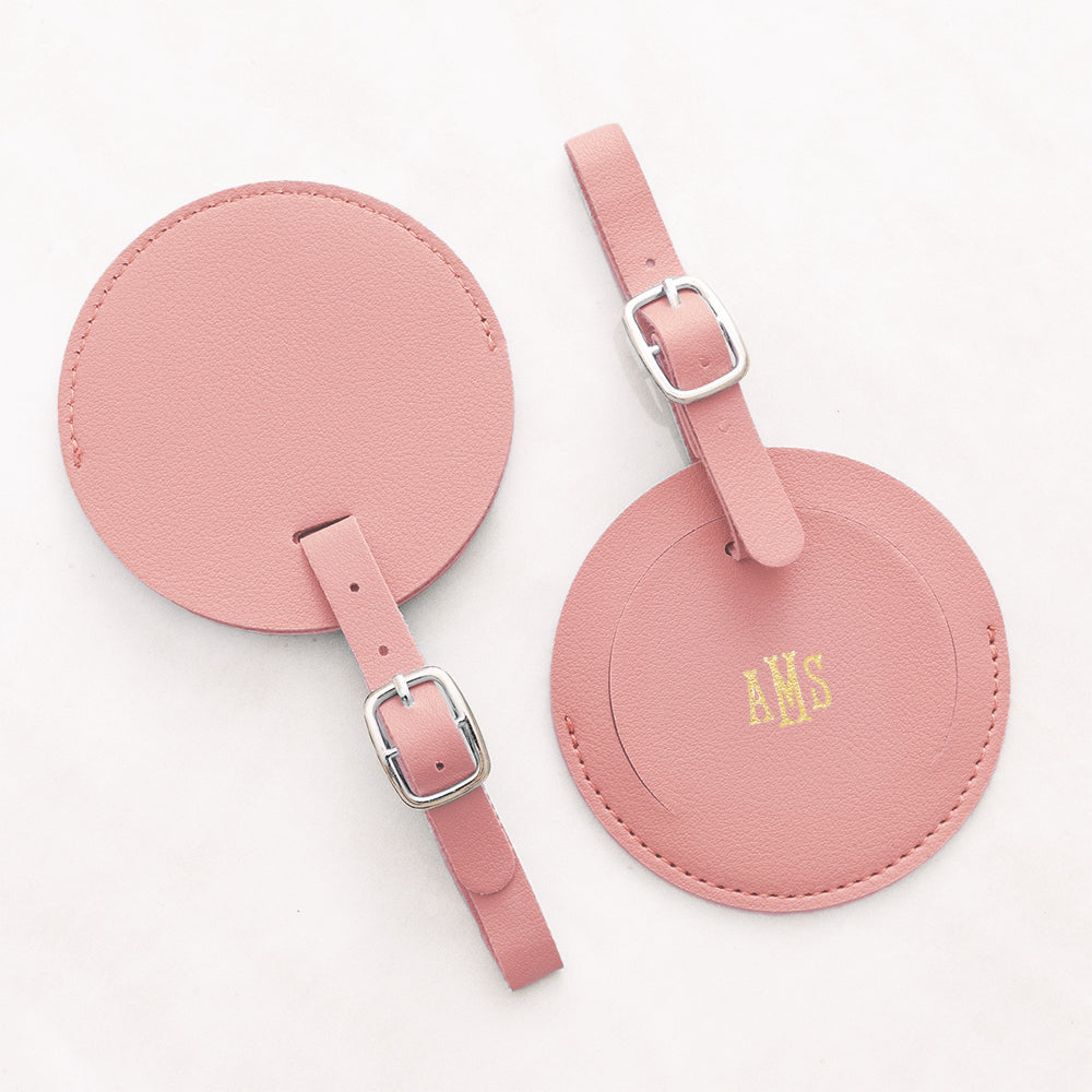 Two pink round luggage tags with straps on a white background