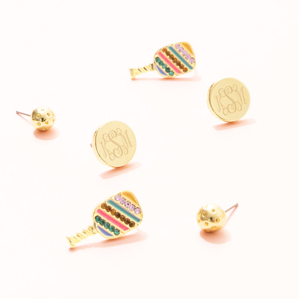 Gold monogrammed earring studs, gold ball studs, and colorful pickleball paddle earrings on a white background