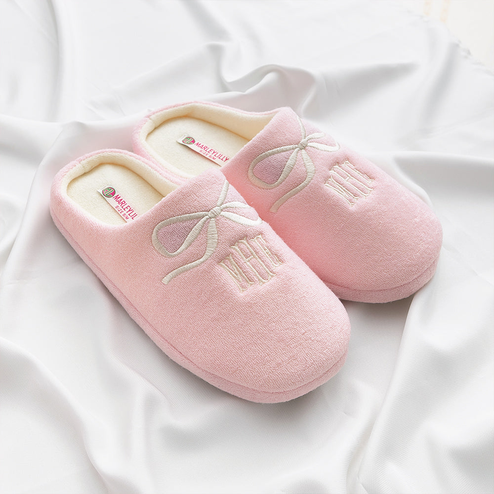 pink bows slippers held by girl on white sheet