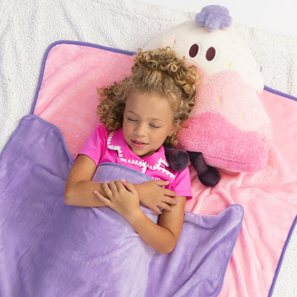 pink kids blanket pillow with jaxy laying down