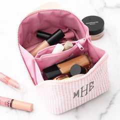 Pink makeup bag with cosmetic products on a marble surface