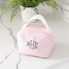 Pink seersucker with monogram 'MHE' on a marble surface with a plant in the background