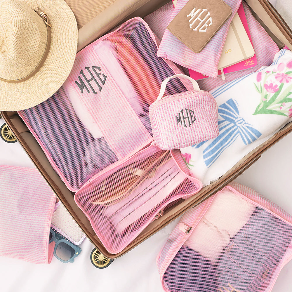 Pink travel organizers with monogram initials on a suitcase