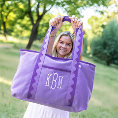 Woman holding a purple tote bag with 'KBM' monogram in a park setting