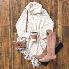 cable knit poncho sweater with riding boots and crossbody