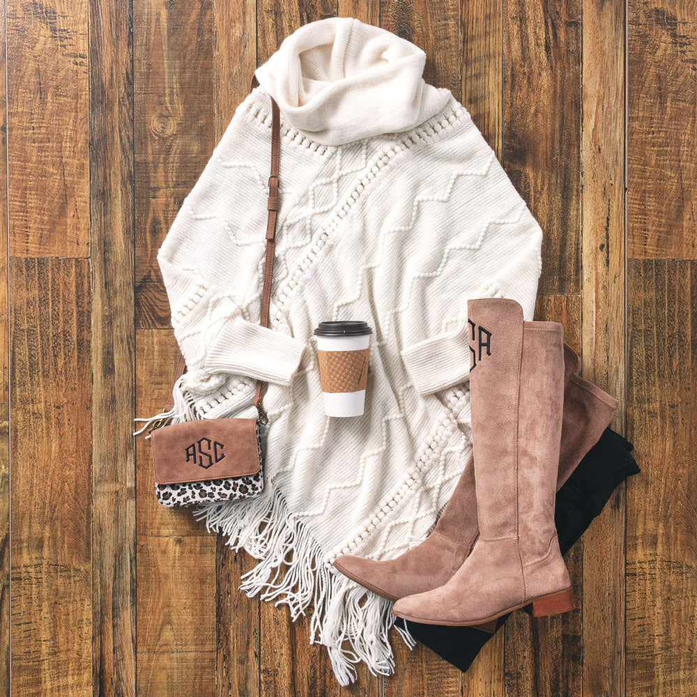 cable knit poncho sweater with riding boots and crossbody