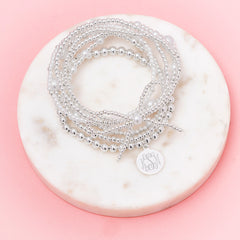 silver pearl bow bracelet stack in marble dish