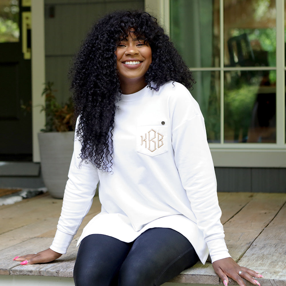 white crewneck sweatshirt on girl sitting on cabin porch