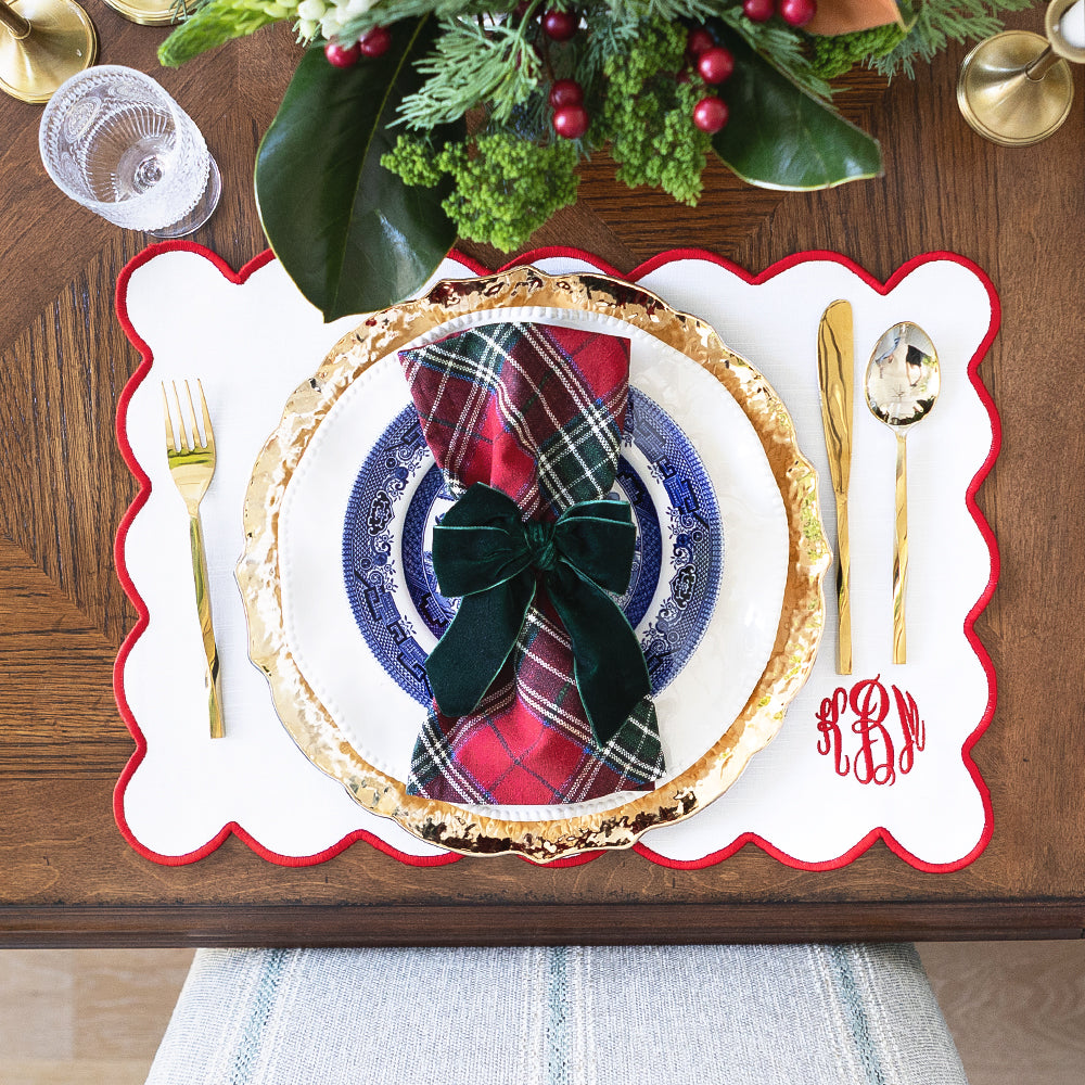 red scalloped placemat christmas setting from above with plaid napkins