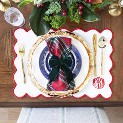 red scalloped placemat christmas setting from above with plaid napkins