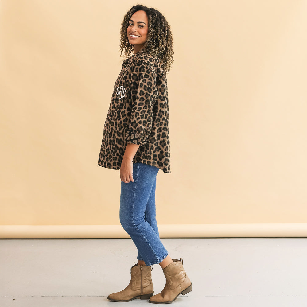 Woman wearing a leopard print top and blue jeans against a beige background