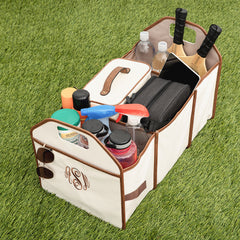 Car trunk organizer with various items on a grass background