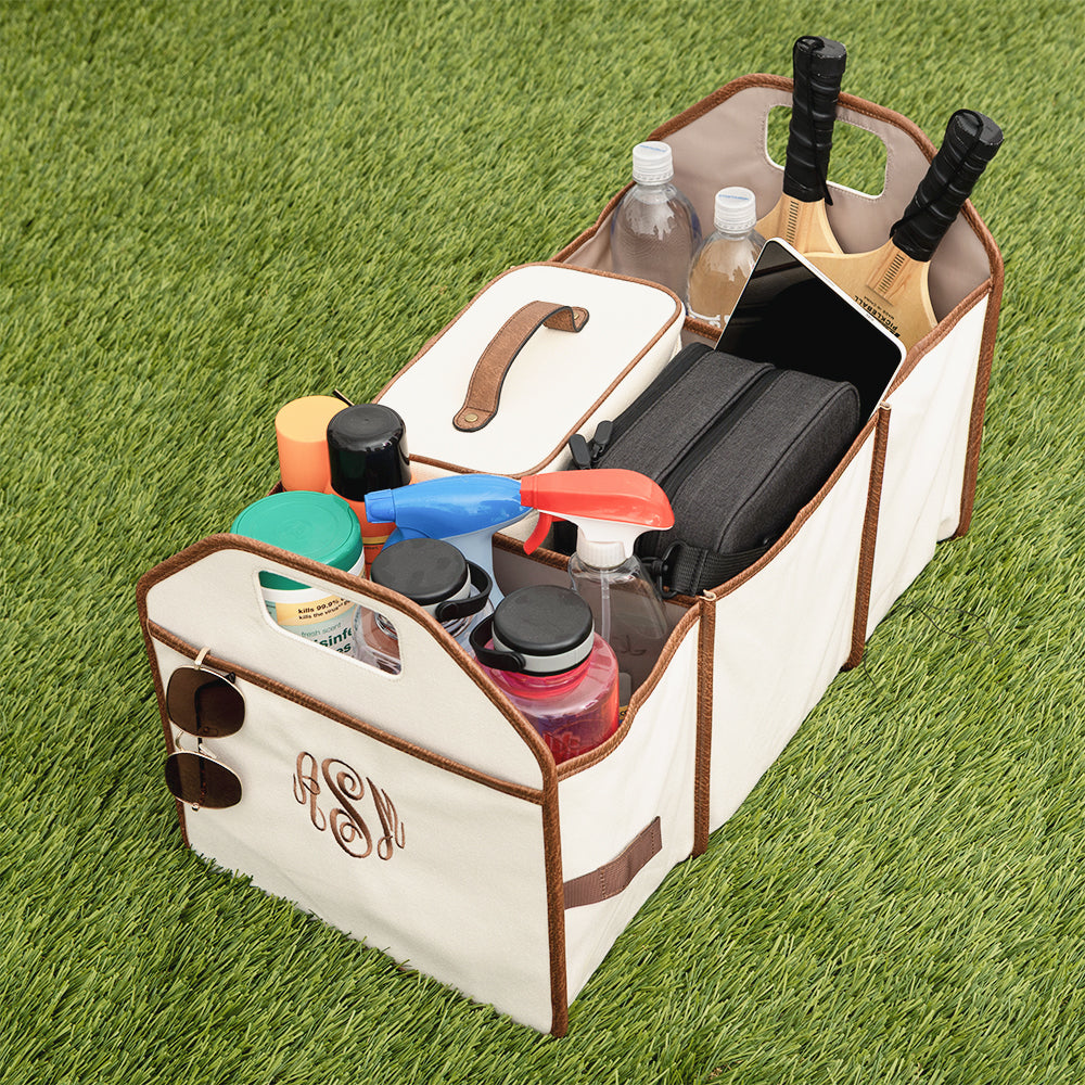 Car trunk organizer with various items on a grass background
