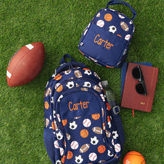 sports ball backpack and lunchbox flatlay on grass