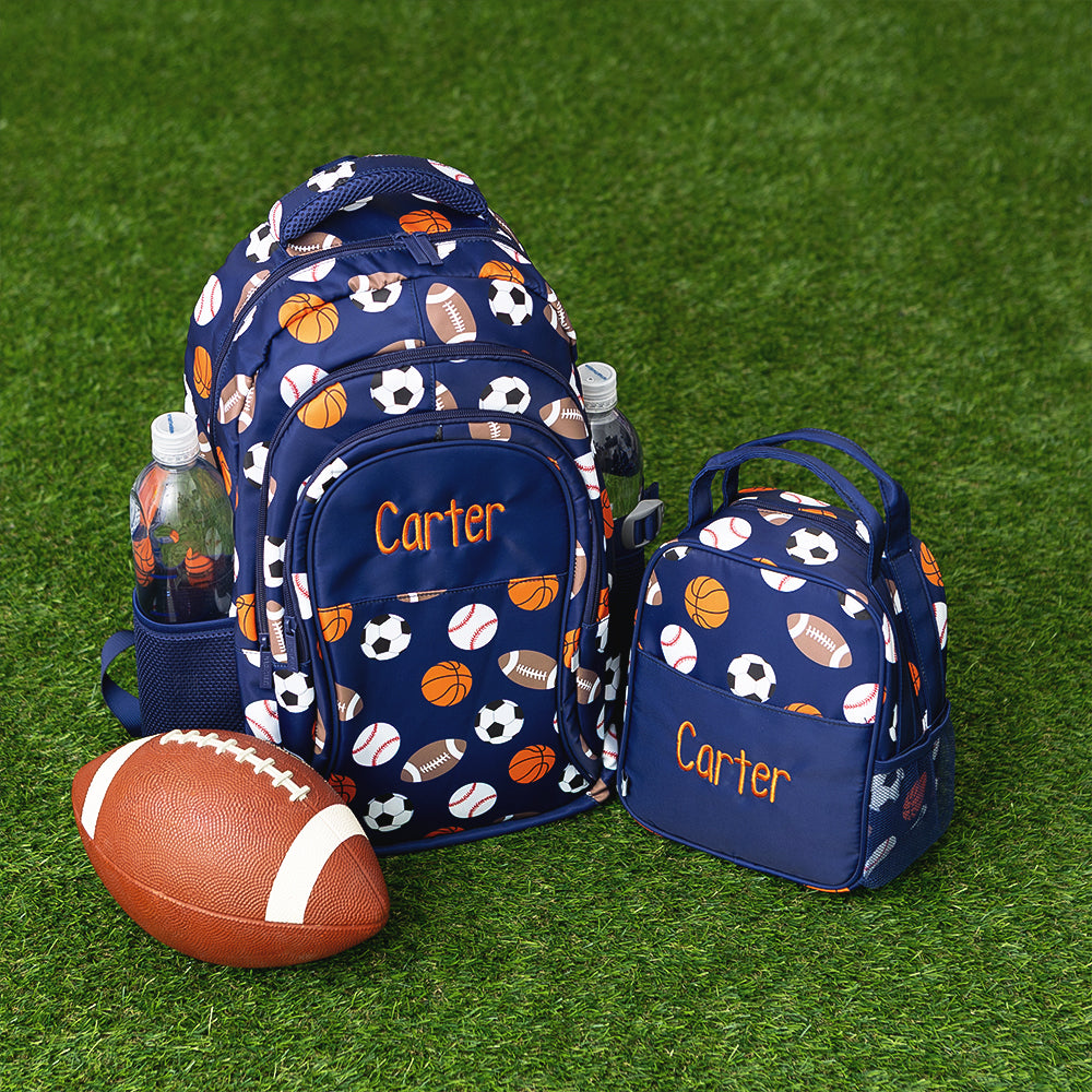 sports ball lunch box and backpack on grass