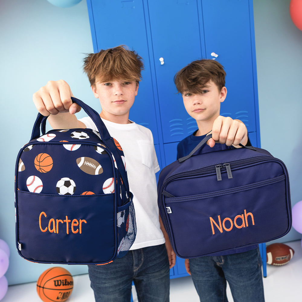 sports balls lunchbox and navy lunchbox held by boys
