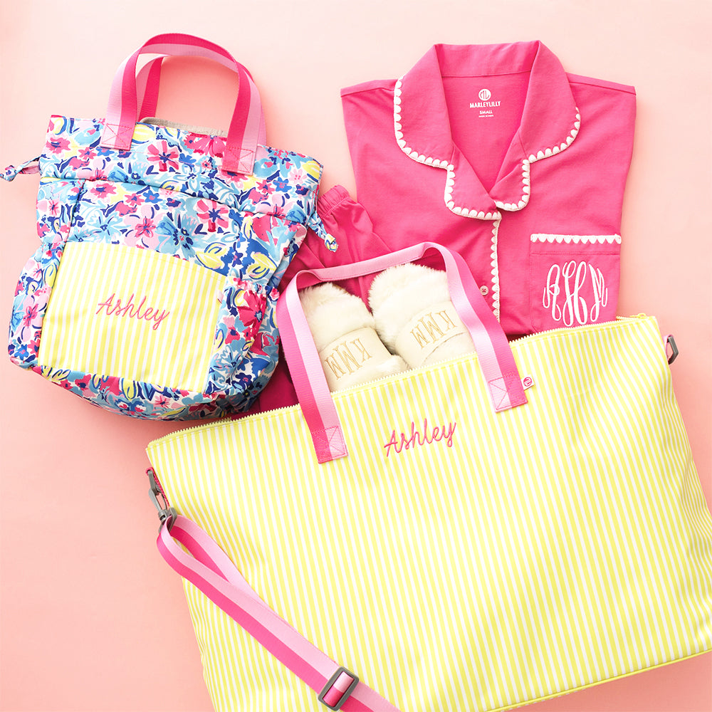 Personalized bags and clothing with 'Ashley' embroidery on a pink background