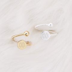 gold and silver monogrammed adjustable rings on faux fur rug