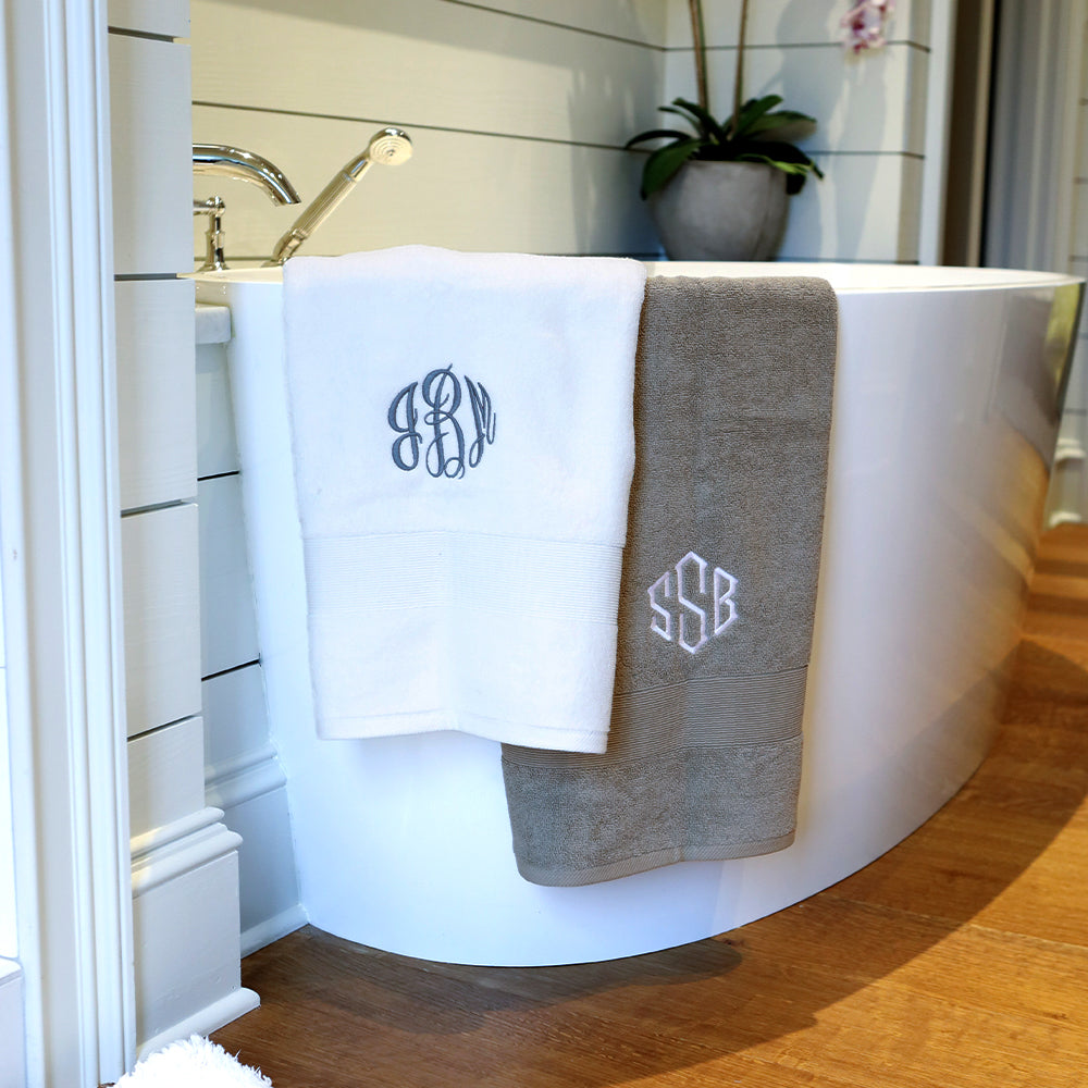 monogrammed bath towel in grey and white hanging off tub