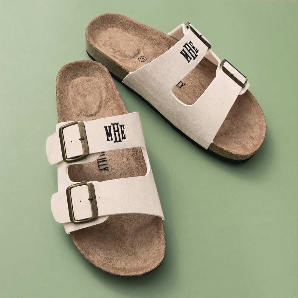Pair of beige sandals with buckles on a green background