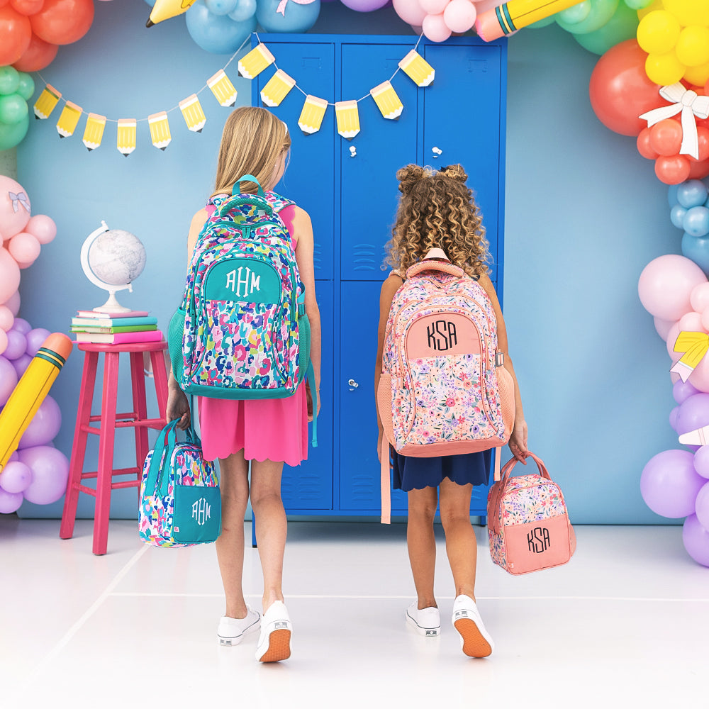two girls carrying monogrammed backpacks in watercolor cheetah and coral floral