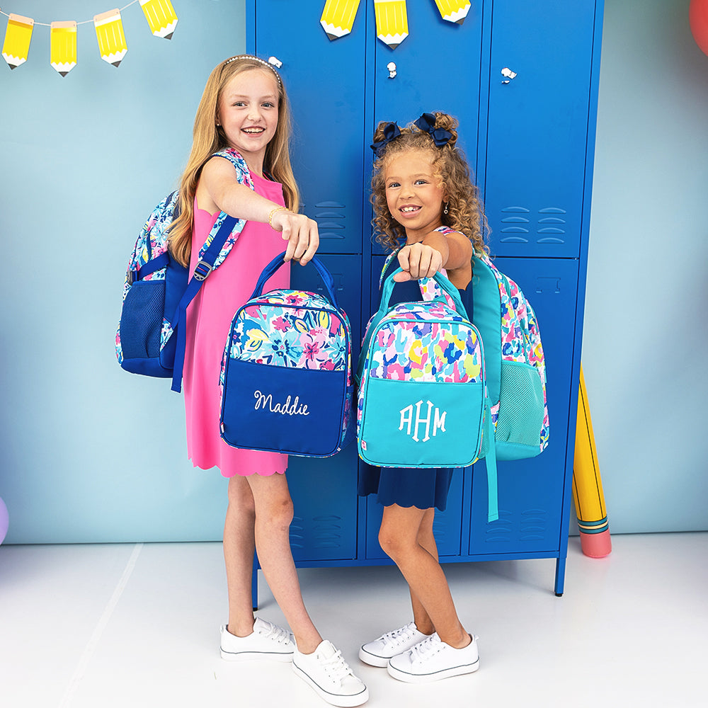 two girls holding watercolor whimsy cheetah lunchboxes and backpacks 