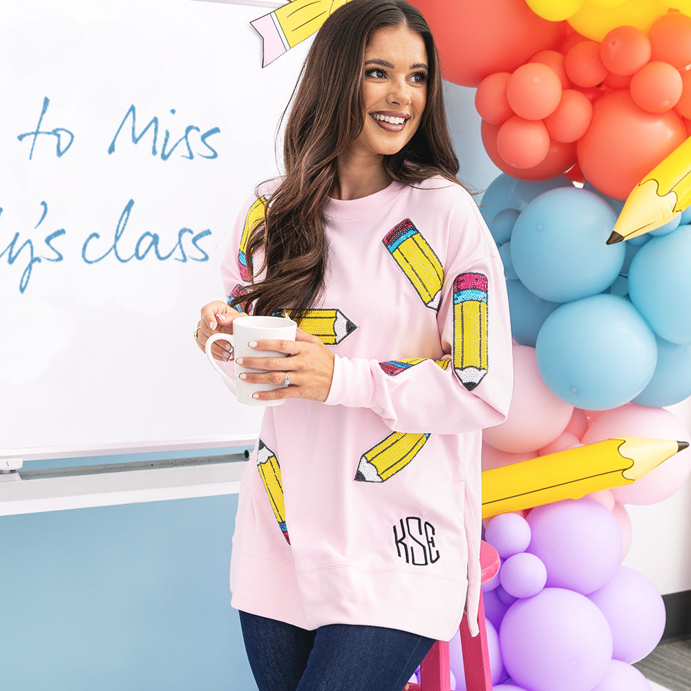 up close of girl wearing monogrammed sequin teacher sweatshirt in pink pencils with white board