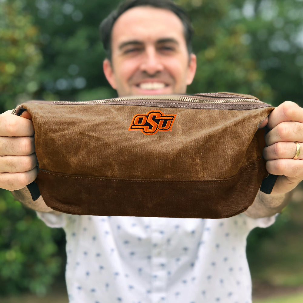 Man holding Oklahoma State Cowboys Waxed Canvas Dopp Kit