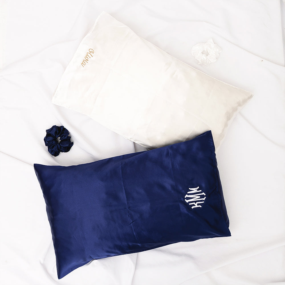Navy satin pillowcase with monogram on a white surface