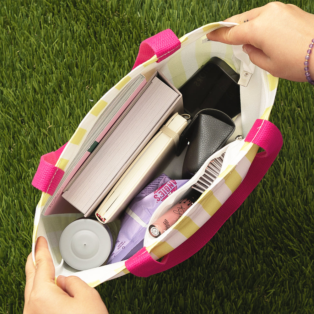 interior of striped tote bag with books, snacks, and miscellaneous items